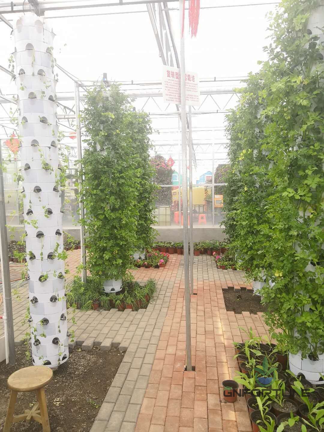 Vertical hydroponic tower garden installed on a balcony terrace with leafy greens