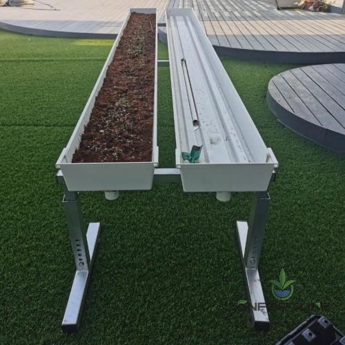 PVC growing channel mounted on a support stand with substrate and plants